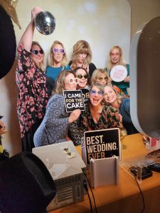 Guests posing with themed photo booth props at wedding